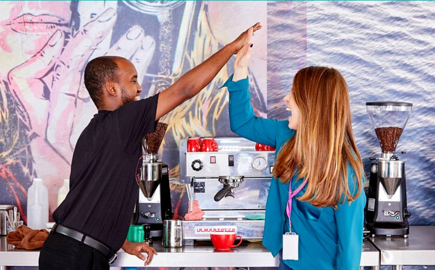 two people high five by a coffee machine