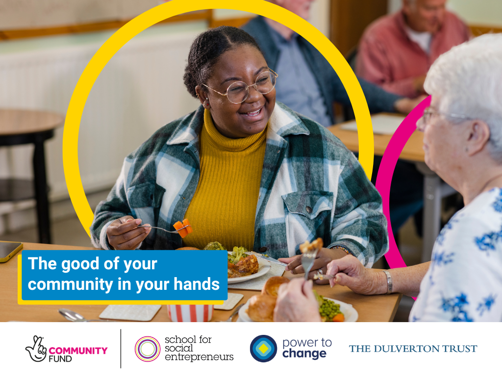 Smiling people enjoying a meal together in a community hub. A graphic reads 'the good of your community in your hands'.
