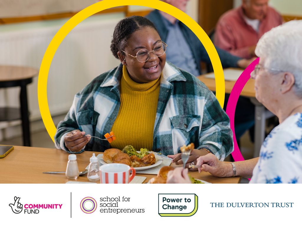 Two people laughing while eating a meal together. At the bottom are the logos for The National Lottery Community Fund, School for Social Entrpreneurs, Power To Change, The Dulverton Trust