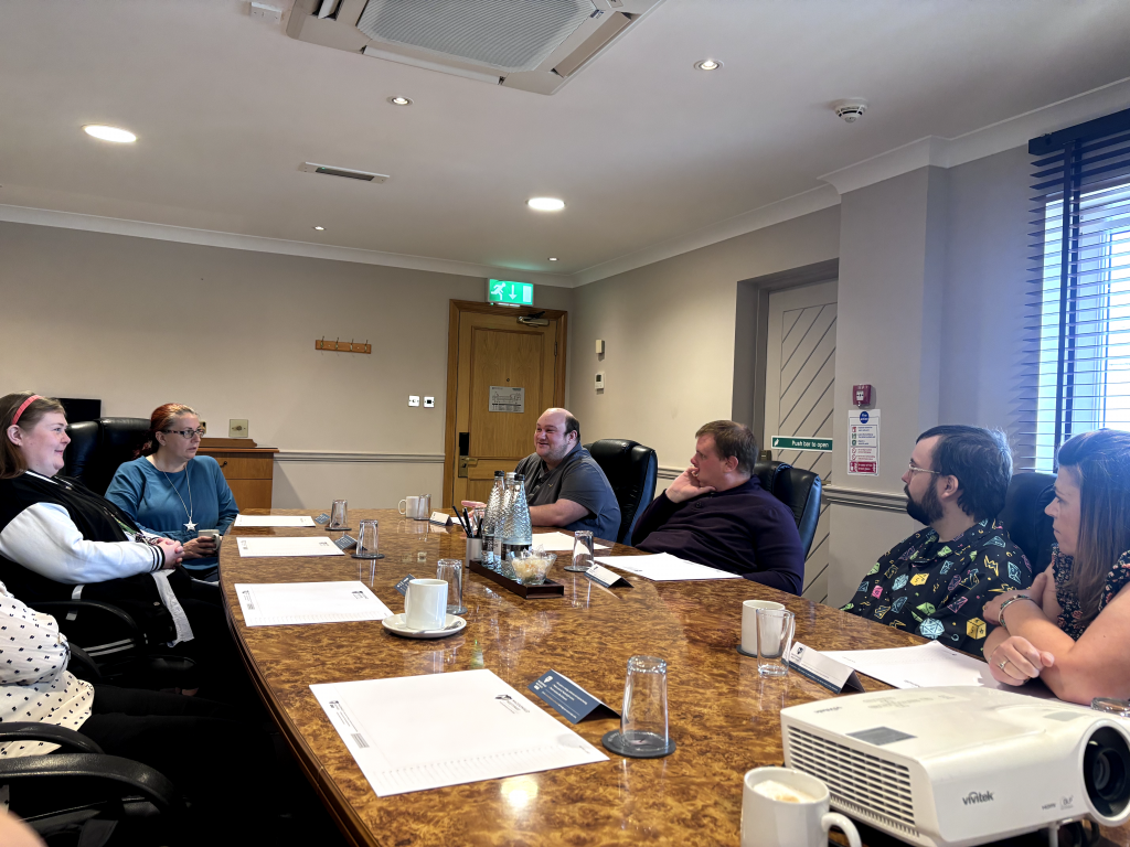 People sit around a large meeting room table with documents in front of them.